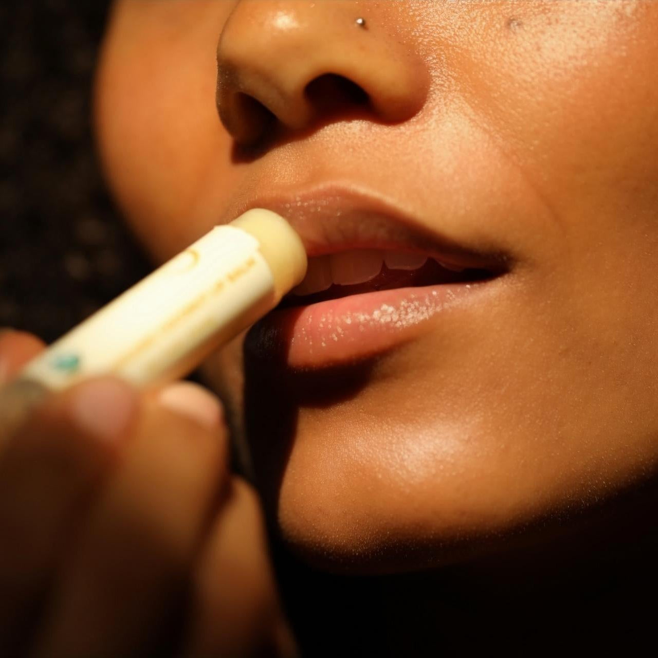 Close-up of a person applying a lip balm or lip stick to their lips.