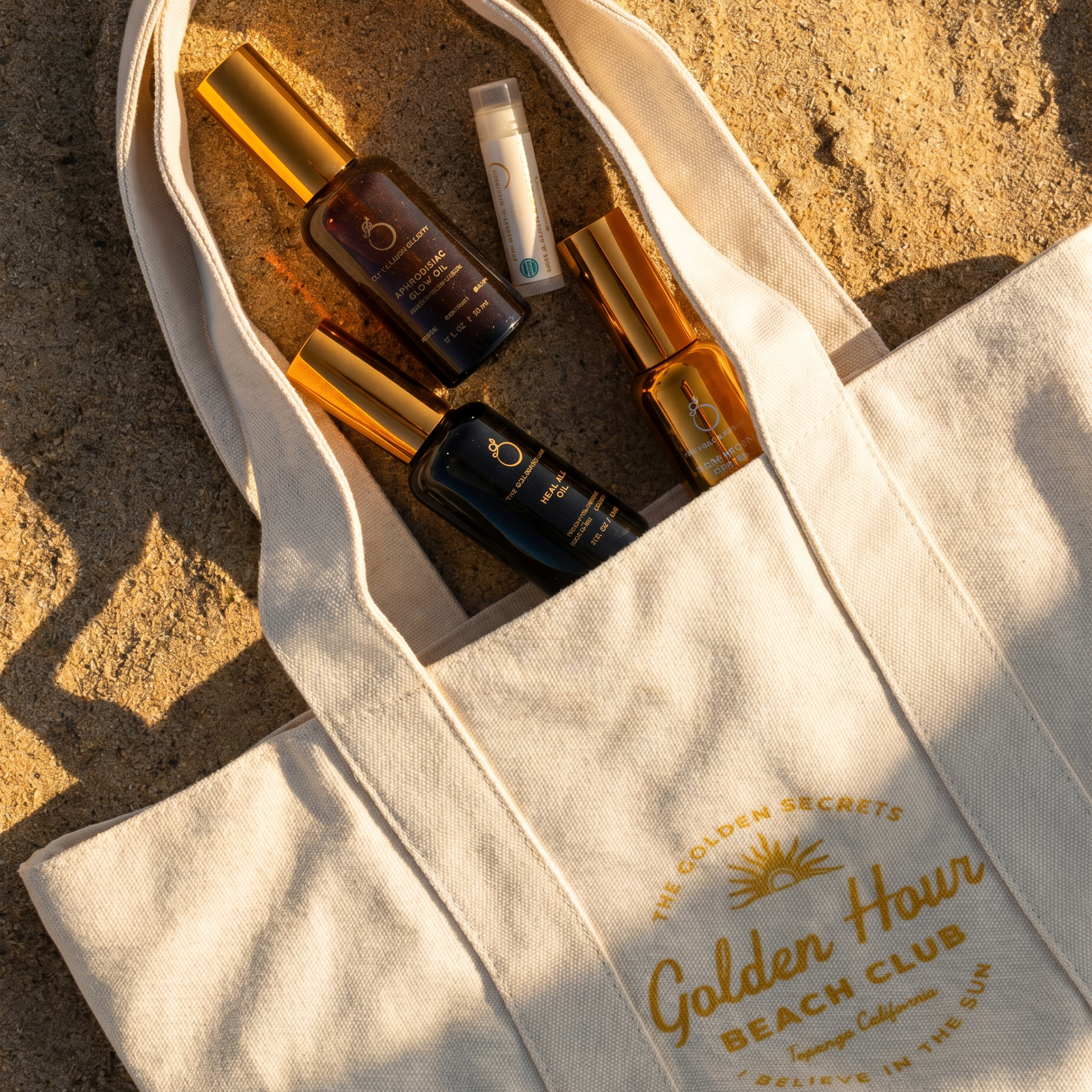 Tote bag with 'Golden Hour Beach Club' branding on a sandy background