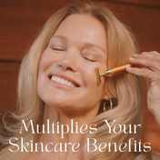 A smiling woman gently uses THE GOLDEN SECRETS Gold Pulse Firming Face Wand—24k gold-plated—on her cheek, eyes closed in serene relaxation. Text on image reads: Multiplies Your Skincare Benefits.