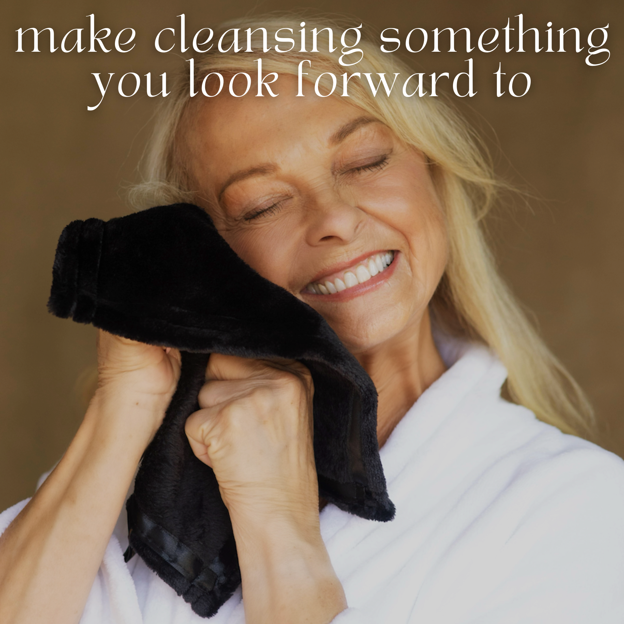 A smiling woman in a white robe gently presses THE GOLDEN SECRETS Glowing Facial Cloths—ultra-soft and black—against her cheek. Above her, the text reads: “make cleansing something you look forward to.”.
