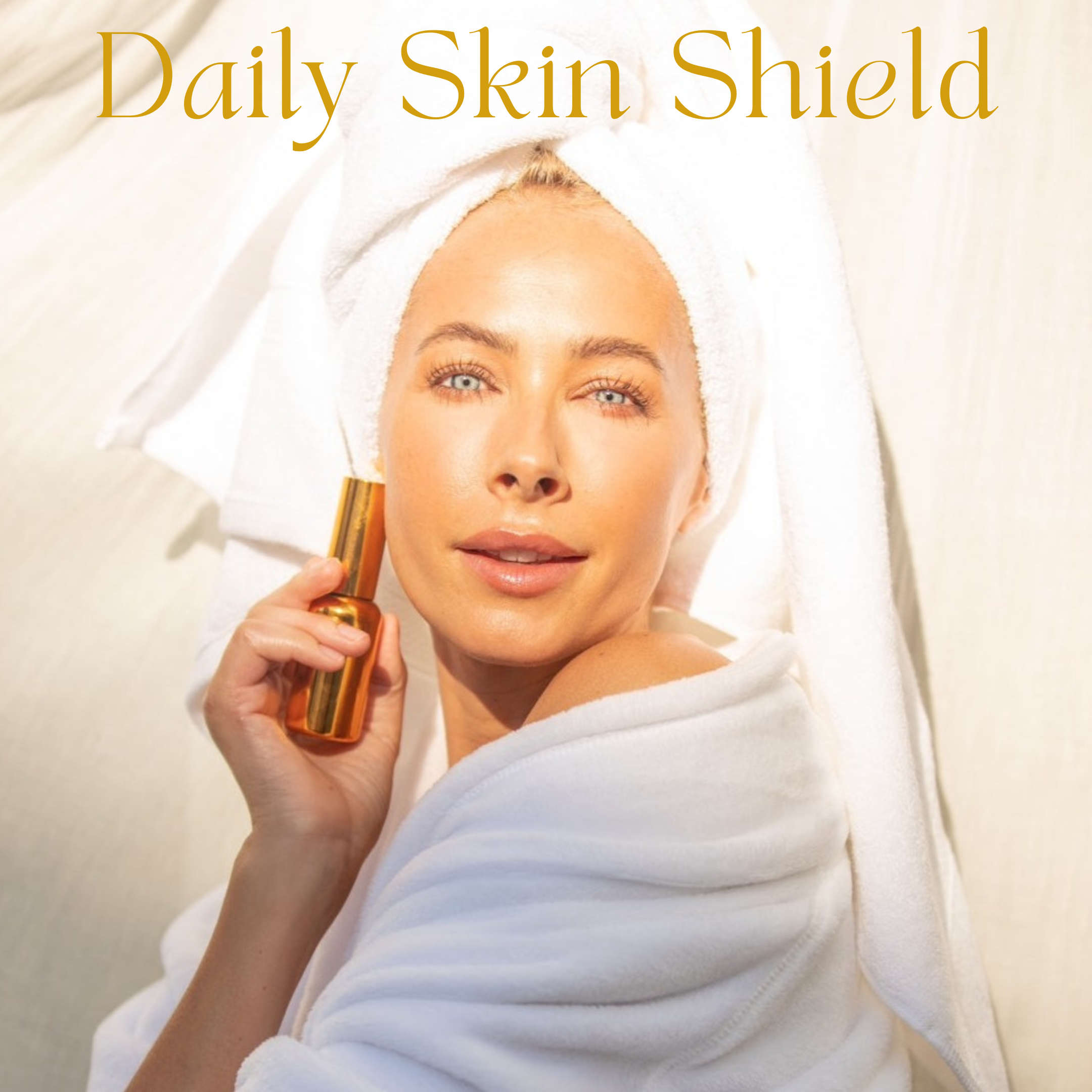 A woman in a white robe and towel holds THE GOLDEN SECRETS Dynamic Duo bottle near her face. Sunlight highlights her clear skin, radiant from her favorite hydrating mist. The text Dynamic Duo appears above her in gold letters.