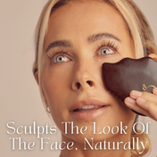 A woman with long lashes and blonde hair uses THE GOLDEN SECRETS Ultimate Glow Trio Kit Gua Sha tool on her cheek. Text reads: Sculpts The Look Of The Face, Naturally. A soft, neutral background highlights the Ultimate Glow Trio Kit—the perfect way to hydrate skin and enhance your natural radiance.