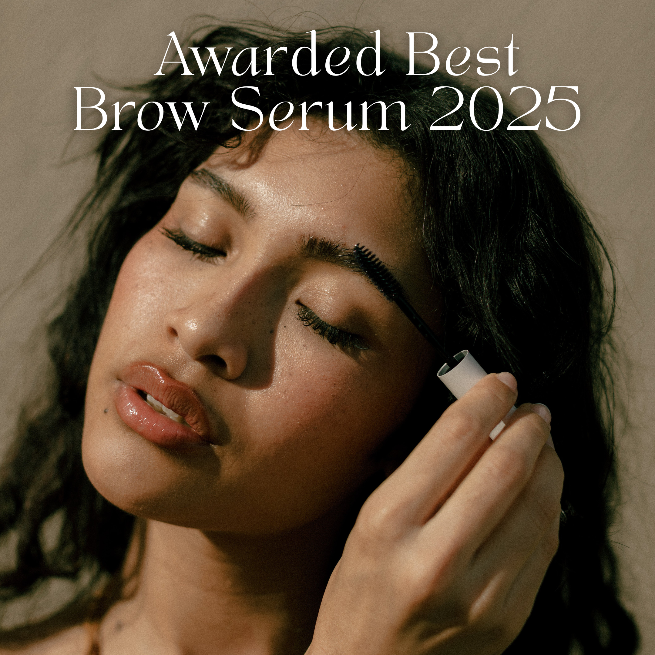 A woman applies THE GOLDEN SECRETS Lash & Brow Duo to her eyebrow with a brush, achieving beautifully defined brows. The text above reads, Awarded Best Brow Serum 2025.