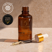A dropper-topped amber bottle of THE GOLDEN SECRETS Body Sculpting Kit Body Oil sits on a beige surface, making it an ideal complement to your body care routine. EWG VERIFIED and THINK DIRTY VERIFIED logos are displayed in the top left corner.