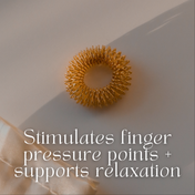 A Gold Reflexology Acupressure Massage Ring by THE GOLDEN SECRETS rests on a beige surface with text: Stimulates finger pressure points + supports relaxation.