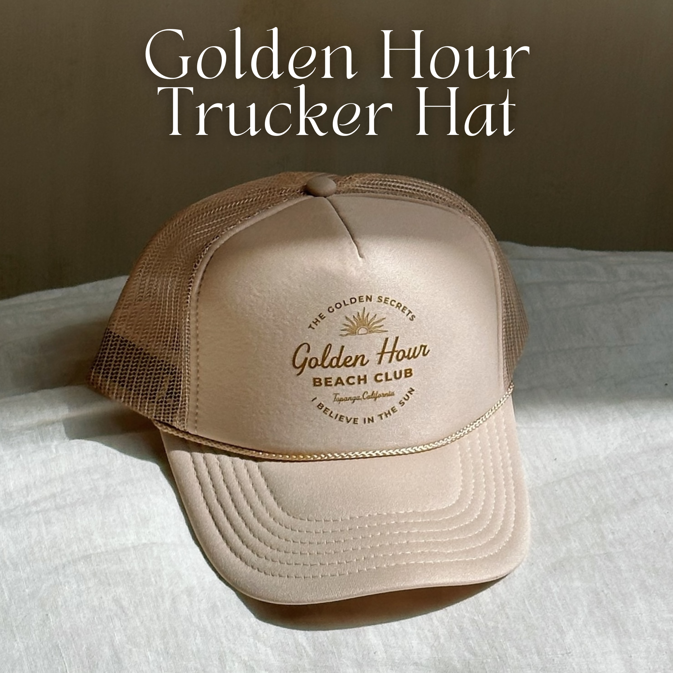 The Golden Secrets Trucker Hat by THE GOLDEN SECRETS features a beige and brown design with the Golden Hour Beach Club sunburst logo on the front, resting on a light surface with gentle sunlight and soft shadows—ideal for embracing golden hour moments and celebrating your love of nature.