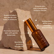 A brown and gold bottle of THE GOLDEN SECRETS Mom & Baby leans against a beige stone. Text labels highlight its benefits: moisture barrier, skin support, balance with botanicals, nourishment, and multipurpose uses—making it the perfect nourishing duo for mom’s changing skin and baby’s delicate barrier. Set against a neutral background.
