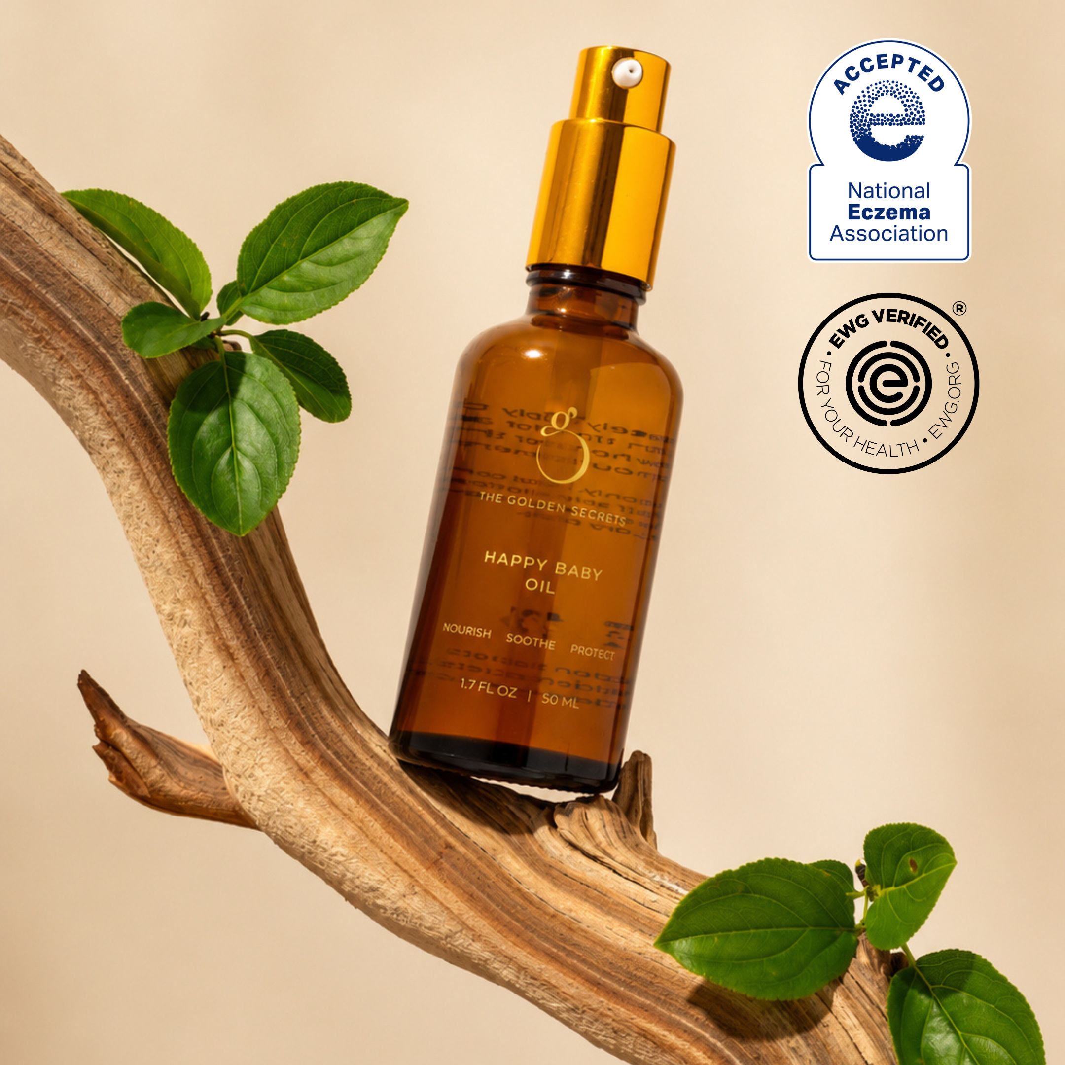 A brown bottle of THE GOLDEN SECRETS Happy Baby Oil, featuring a gold pump, is displayed on a wooden branch with green leaves. Specially formulated for sensitive skin, this organic oil gently soothes dryness. Two certification logos—National Eczema Association Accepted and EWG Verified—are shown.