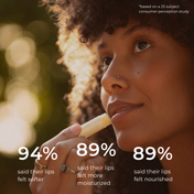 A woman with curly hair applies THE GOLDEN SECRETS Organic Coconut Lip Balm outdoors. On-screen text: 94% felt softer lips, 89% felt more moisturized lips, and 89% felt nourished lips.* Results based on a consumer perception study of 25 participants. Perfect for hydrating dry lips and helping you achieve naturally plump lips.