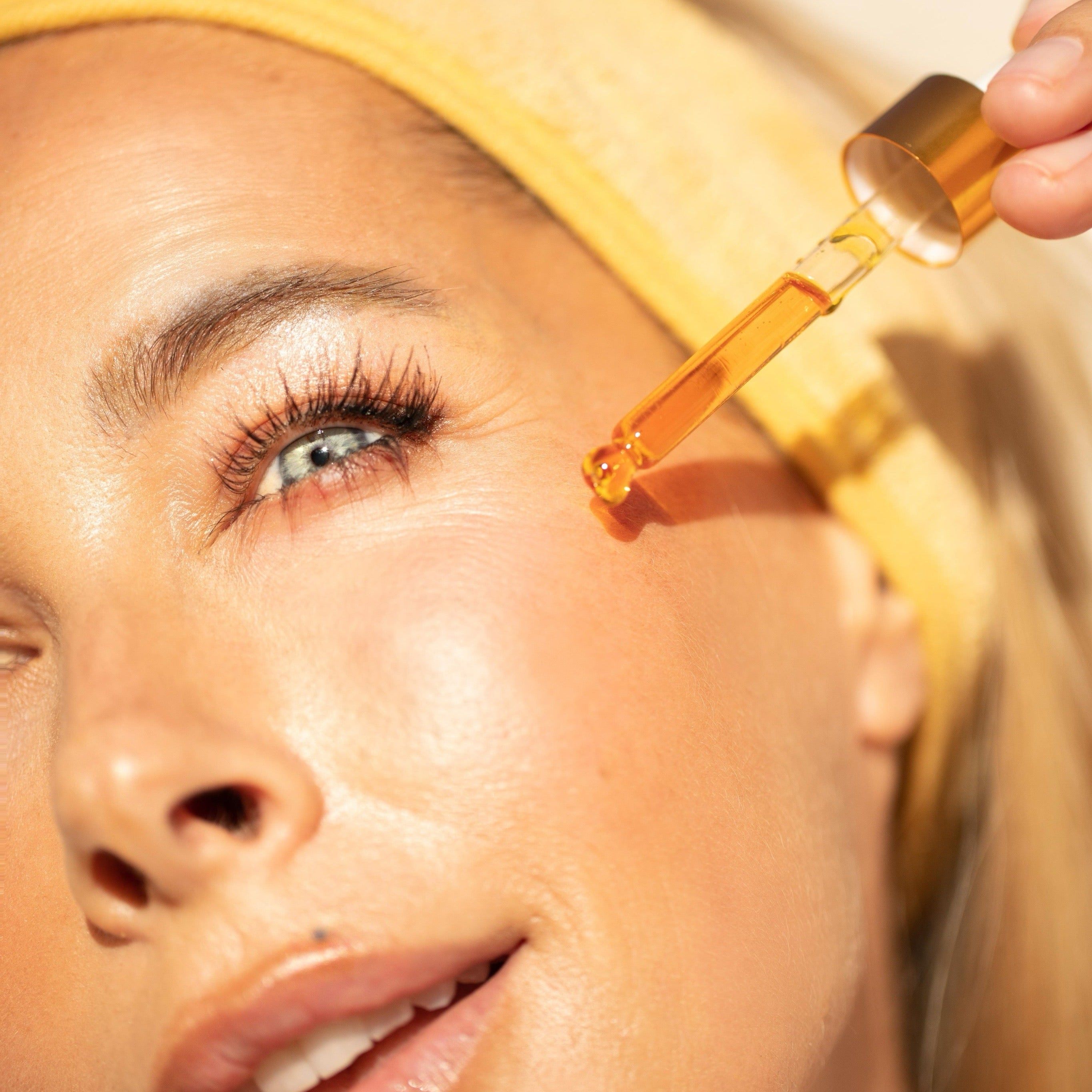 woman with youth beauty face oil dropper on cheek